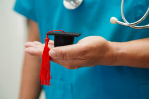 A healthcare professional holds a graduation cap, symbolizing career growth