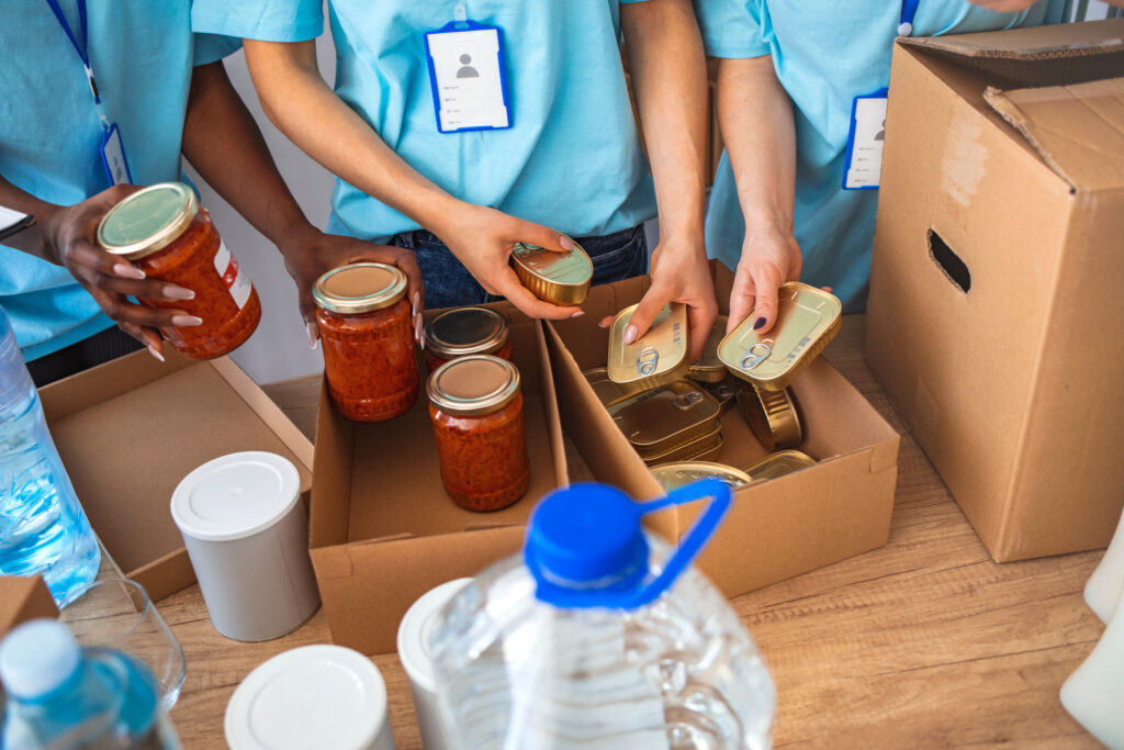  Group of people sort through donated food items while volunteering in community food bank