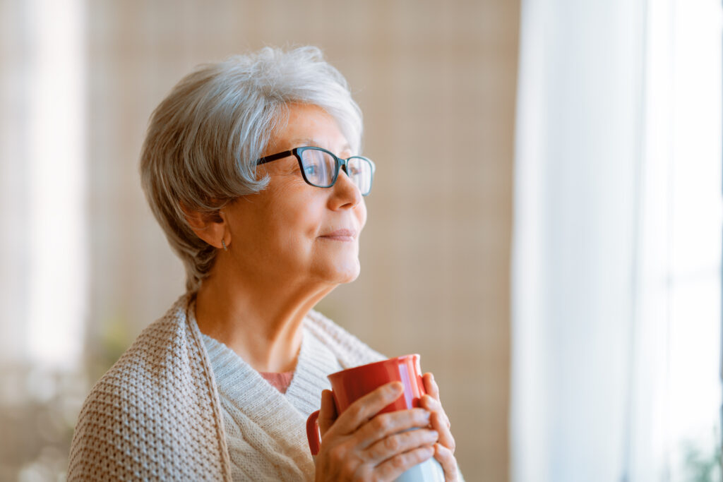 Older woman staying warm with a blanket and warm beverage