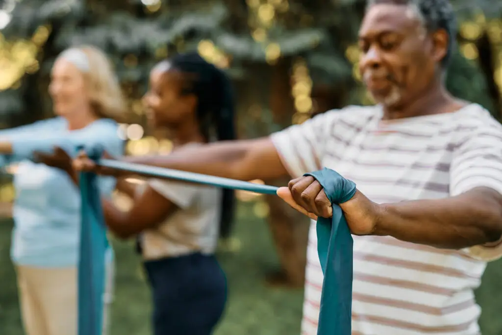 Older adults exercising with resistance bands outdoors, building strength and balance for healthy aging at home.