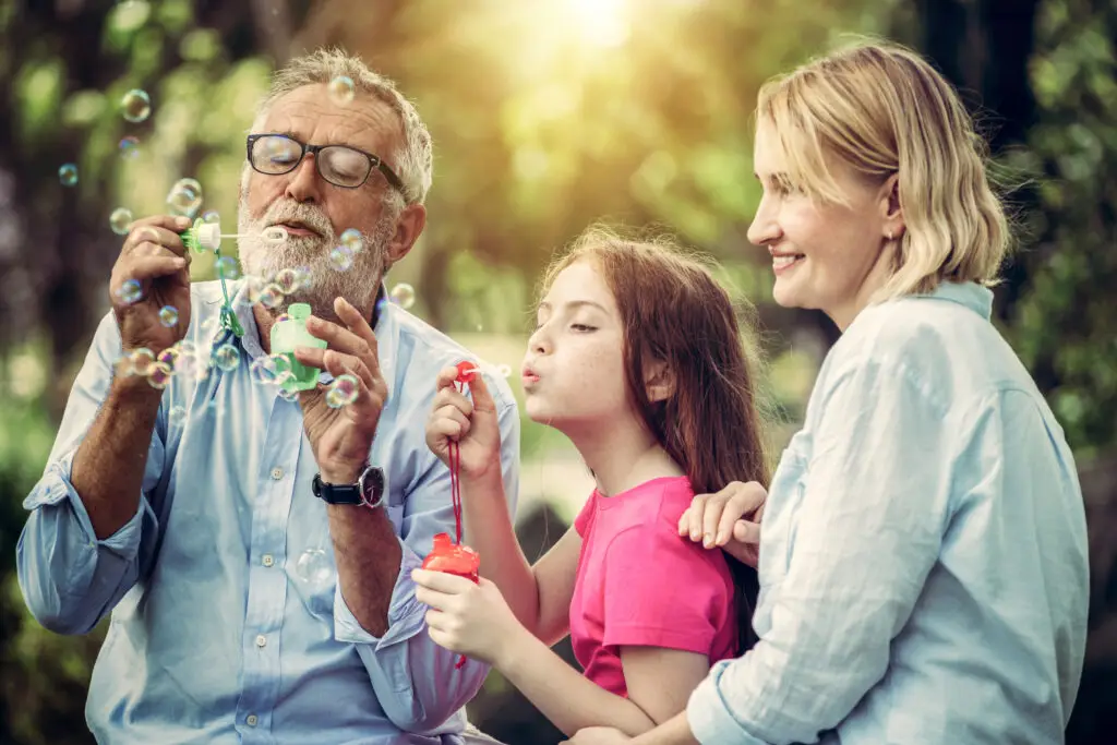 Mother, daughter, and grandfather blowing bubbles.