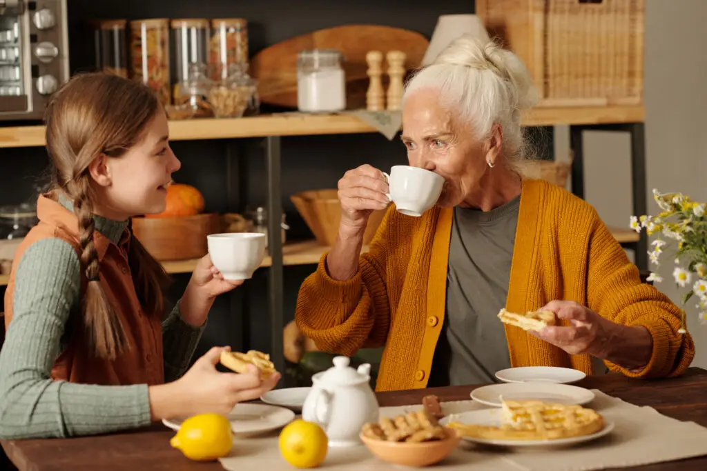 Grandmother and grandchild drinking tea and eating apple pie.