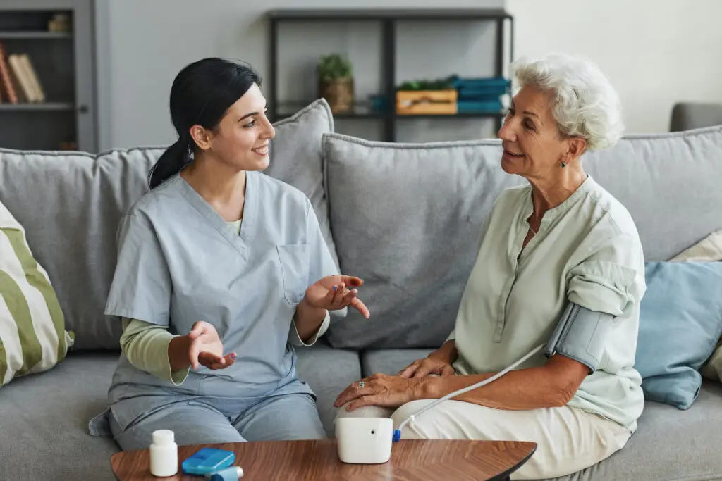 Femal home health aid talking to a patient at home.