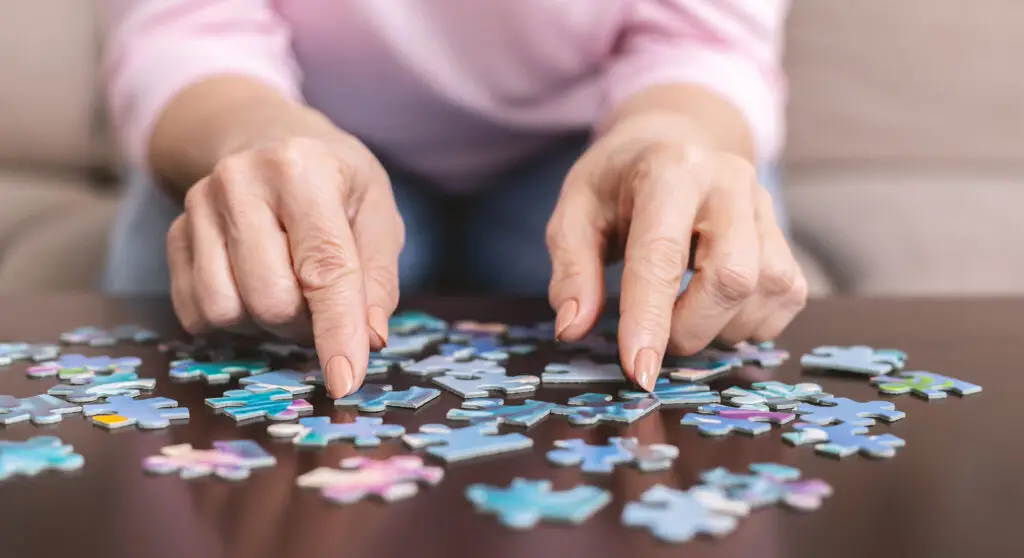 Older adult working on a jigsaw puzzle, keeping the mind active to support healthy aging at home.